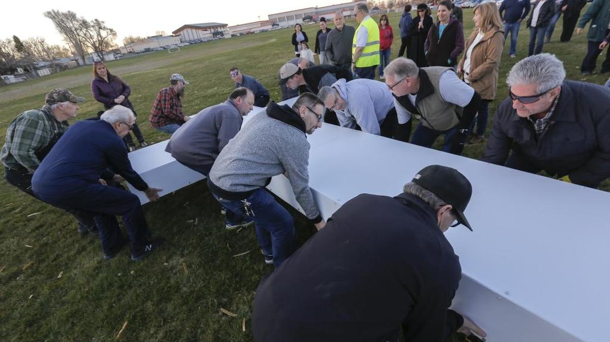 Congregation members of The Living Room Community Church lay a 20-foot illuminated aluminum cross down on the grass at Kennewick High School practice fields before they start rehearsing their cross procession before Easter in Kennewick. The cross procession was being recorded for their production of The Passion in the 21st Century, a contemporary musical reenactment of the Passion of Christ.