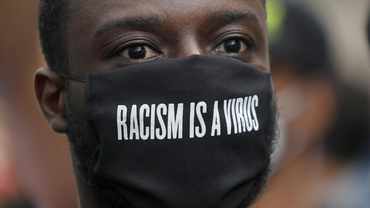 A protester wears a face mask in front of the US embassy, during the Black Lives Matter protest rally in London, Sunday, June 7, 2020, in response to the recent killing of George Floyd by police officers in Minneapolis, which has led to protests in many countries and across the US.