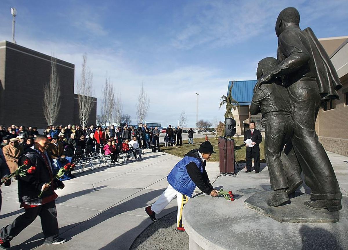 Ellen Ochoa Middle School students Corey Brown, right, and his brother Marcel place roses Monday, Jan. 16, 2012, at a statue of Martin Luther King Jr. at Columbia Basin College in Pasco, Wash., during the 21st annual bell-ringing ceremony. (AP Photo/Tri-City Herald, Richard Dickin)