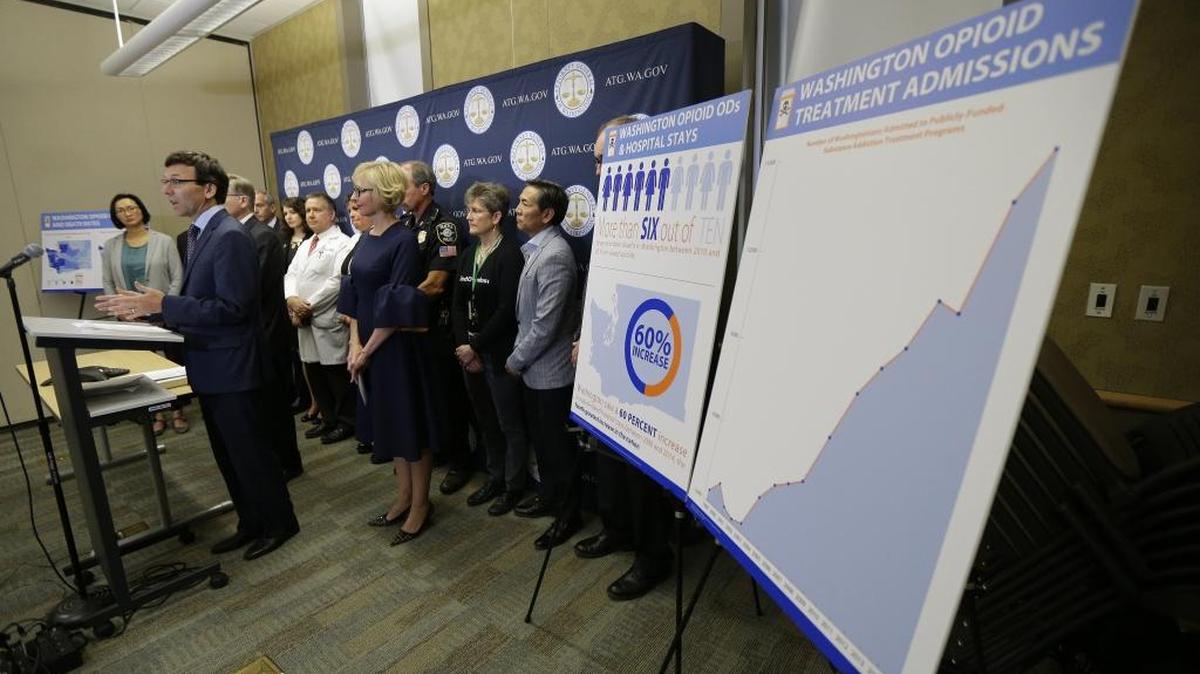 Washington Attorney General Bob Ferguson, second from left, talks to reporters in September in Seattle, as he stands near a chart detailing the increase of admissions for opioid addiction treatment in Washington state. Ferguson said the state and the city of Seattle are filing lawsuits against several makers of opioids, including Purdue Pharma, seeking to recoup costs incurred by government when the drugs, which many officials blame for a national addiction crisis, are abused.
