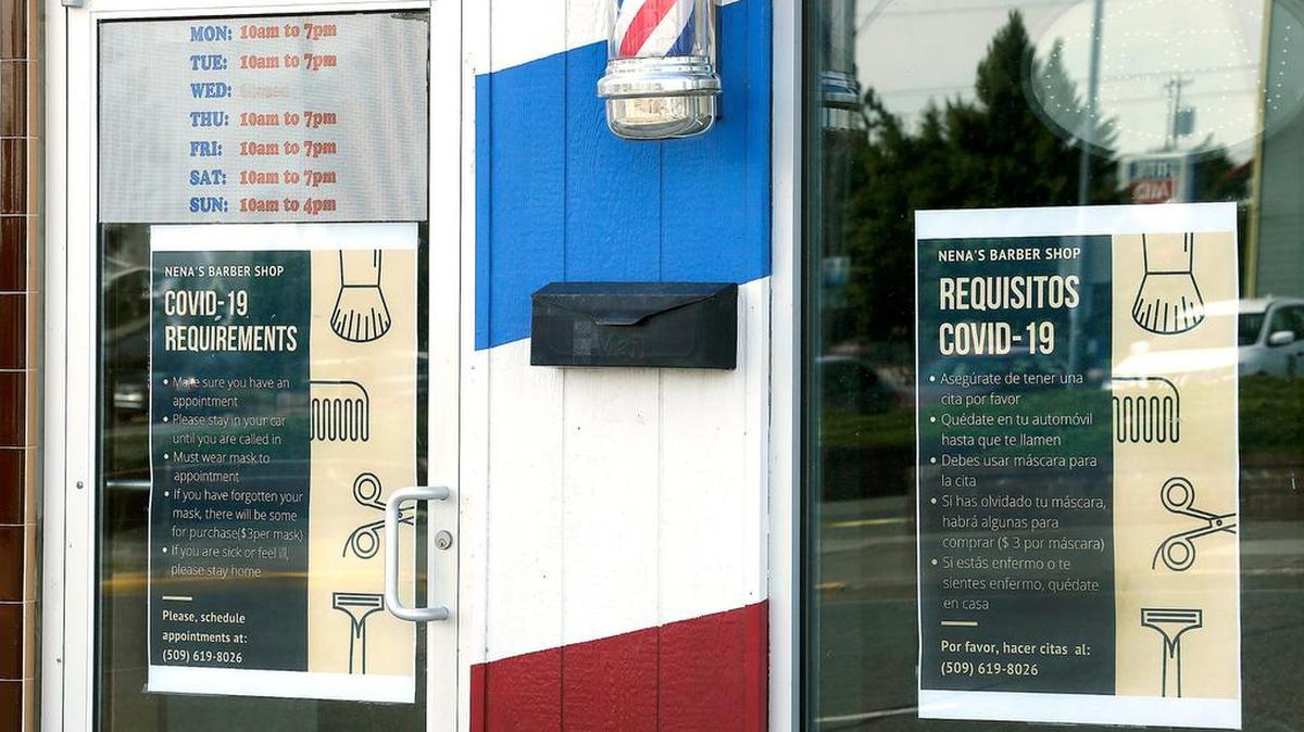 Bilingual posters displayed on the window and door of a downtown Pasco barber shop explain to customers the procedures to getting a haircut while the modified reopening is in effect during the coronavirus pandemic. A glitch in the state computer system is making it tough for hairdressers and others to get their occupational licenses.