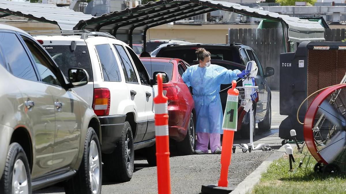 A nurse at the Tri-Cities Community Health in Pasco checks the temperature of a patient last summer in the drive-up coronavirus testing site. Many rural residents have to drive several miles to facilities like this one in order to receive medical attention.