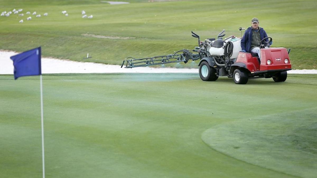 Carl Thompson, course superintendent at Columbia Point Golf Course, applies a liquid fertilizer containing an inert blue dye to the green Monday on the 14th hole at the Richland golf course. Thompson said the coloring helps employees see where the application is covering the ground.