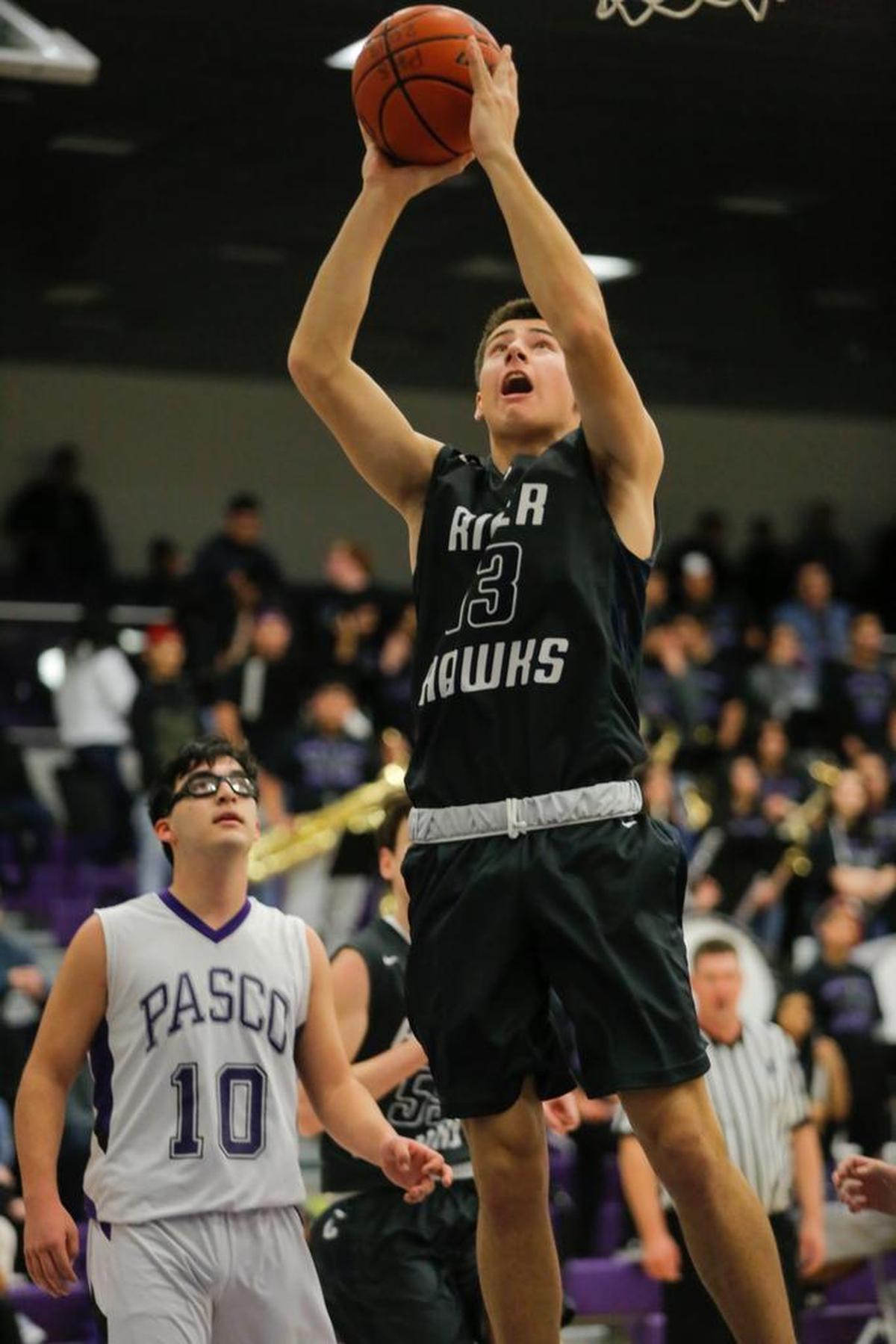 Chiawana’s Seth Schmidt (13) takes a shot as Pasco’s Diego Gutierrez (10) looks on during a Mid-Columbia Conference basketball game Saturday at Pasco High School. Schmidt came off the bench to score 15 points in Chiawana’s 67-56 victory.