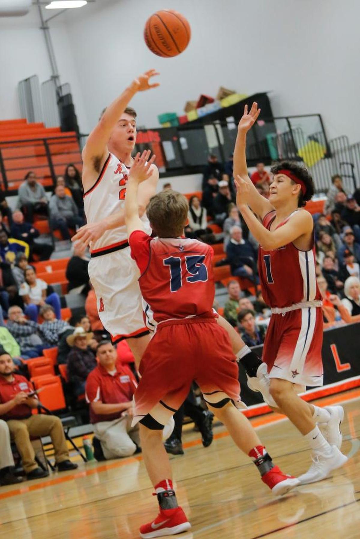 Kennewick's Tyler Pearson (24) makes a pass as Eisenhower's Warren Barreiro (15) and Alejandro Terrazas (1) guard him during a boys basketball game on Friday at Kennewick High School. The Lions beat the Cadets 75-72.