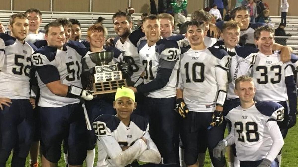 The Tri-Cities Prep football team celebrates with the trophy after defeating DeSales 26-7 in the annual Holy Bowl between the Catholic schools.
