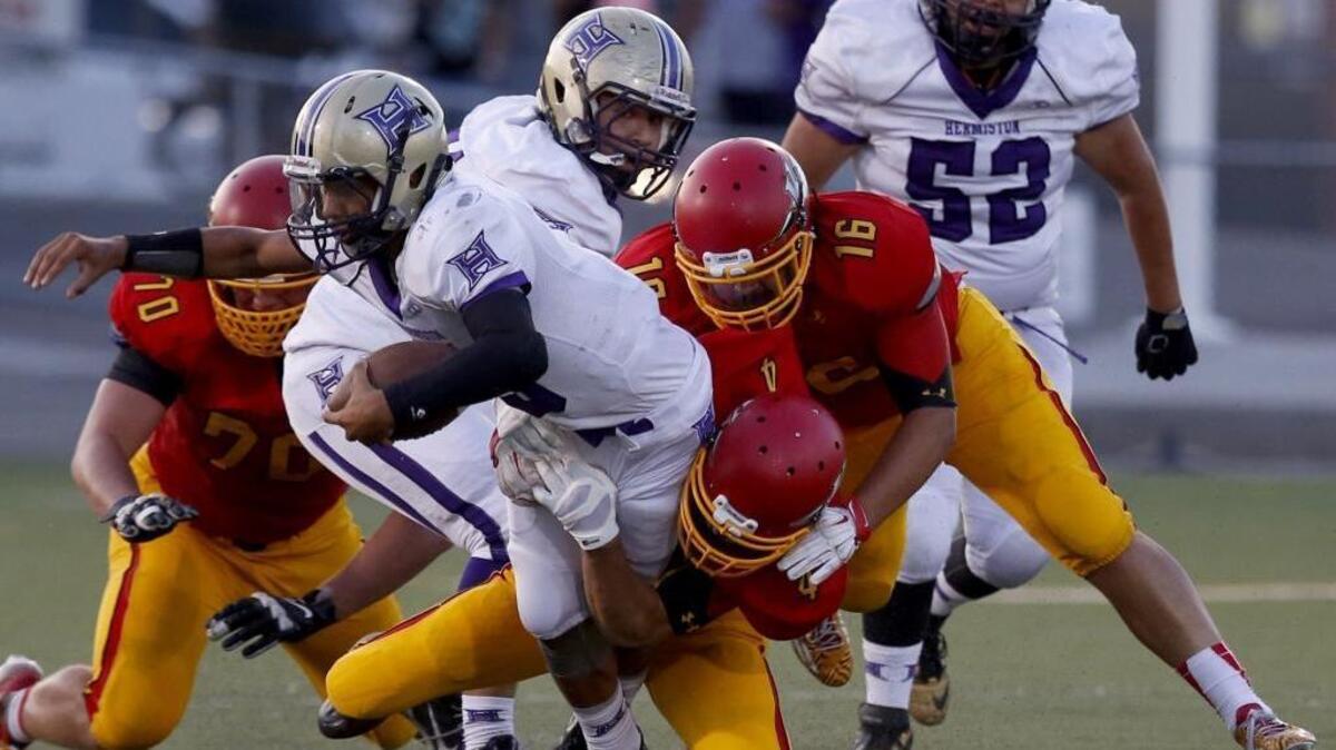 
Kamiakin’s Alex Bayuk (4) and Mike Jones (16) tackle Hermiston’s Dayshawn Neal during Friday’s game at Lampson Stadium in Kennewick. The Braves defeated the Bulldogs 54-6.  See a photo gallery at tricityherald.com
