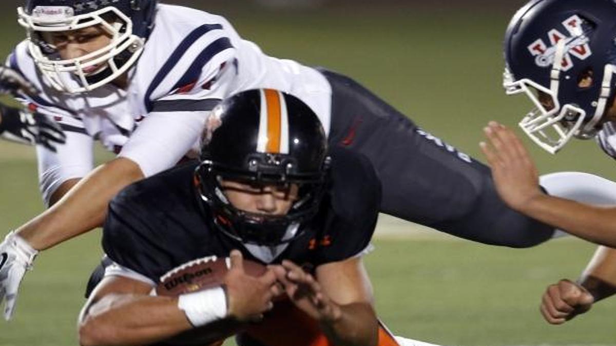 Kennewick’s Raymond Gutierrez dives under Wilson’s Isaiah Clark (44) and Alex Montonaga (12) during Saturday’s Class 3A state playoff game at Lampson Stadium.