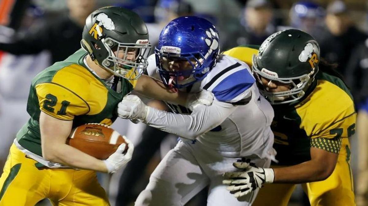 Richland running back Parker McCary (21) slips through a tackle by Bothell’s Peter Davis (33) as Dontae Powell (76) holds him off during Saturday’s playoff game at Lampson Stadium.