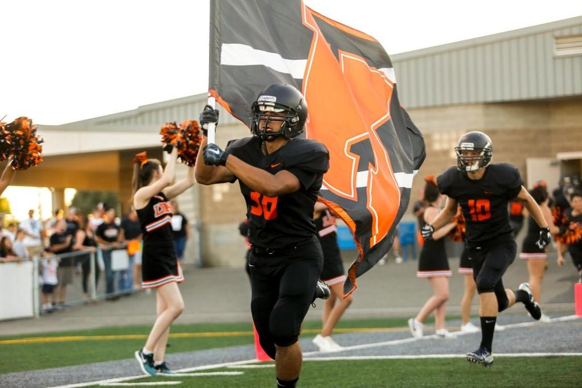 Kennewick’s Cedric Riel (38) runs out on the field holding Kennewick High School's flag before the start of the season opener against Prosser at Lampson Stadium.