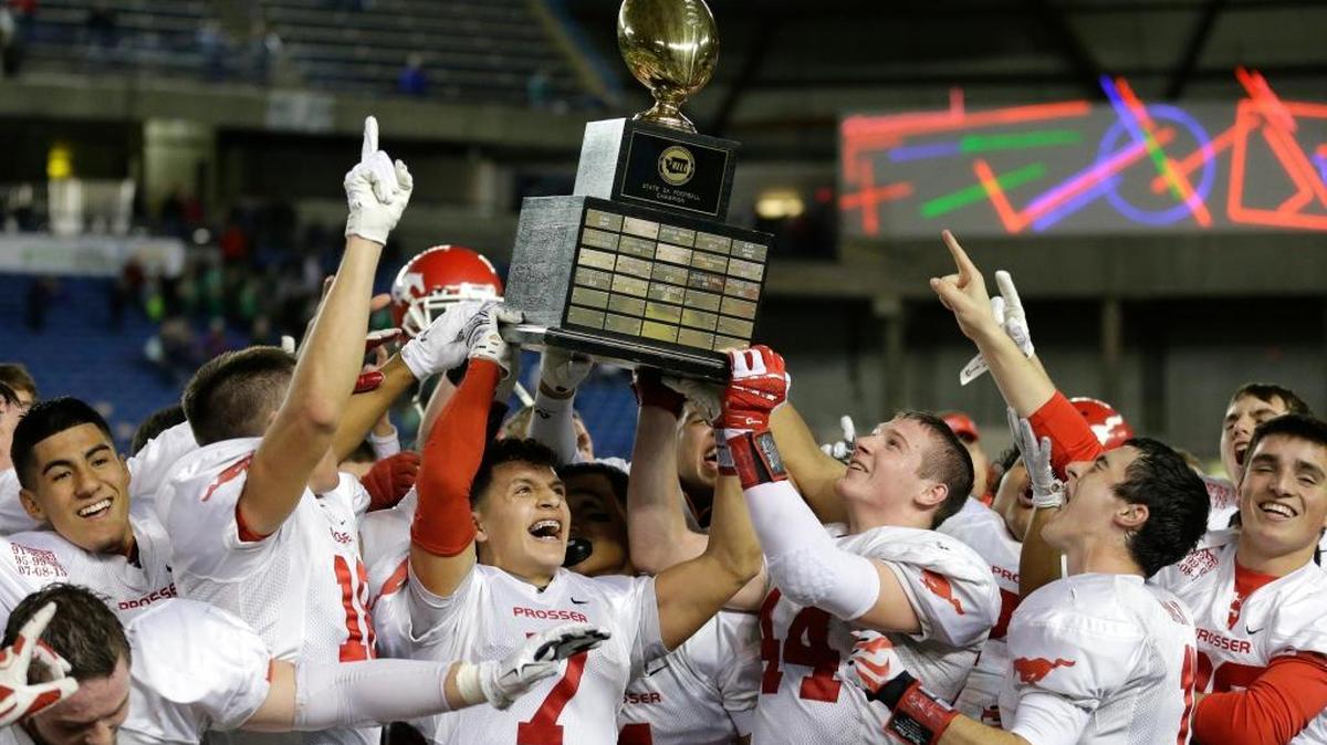 Prosser wide receiver Roy Borrego (7) lifts the trophy with his teammates after Prosser beat Tumwater 22-15 to win the Washington state 2A high school football championship, Saturday, Dec. 5, 2015, in Tacoma.