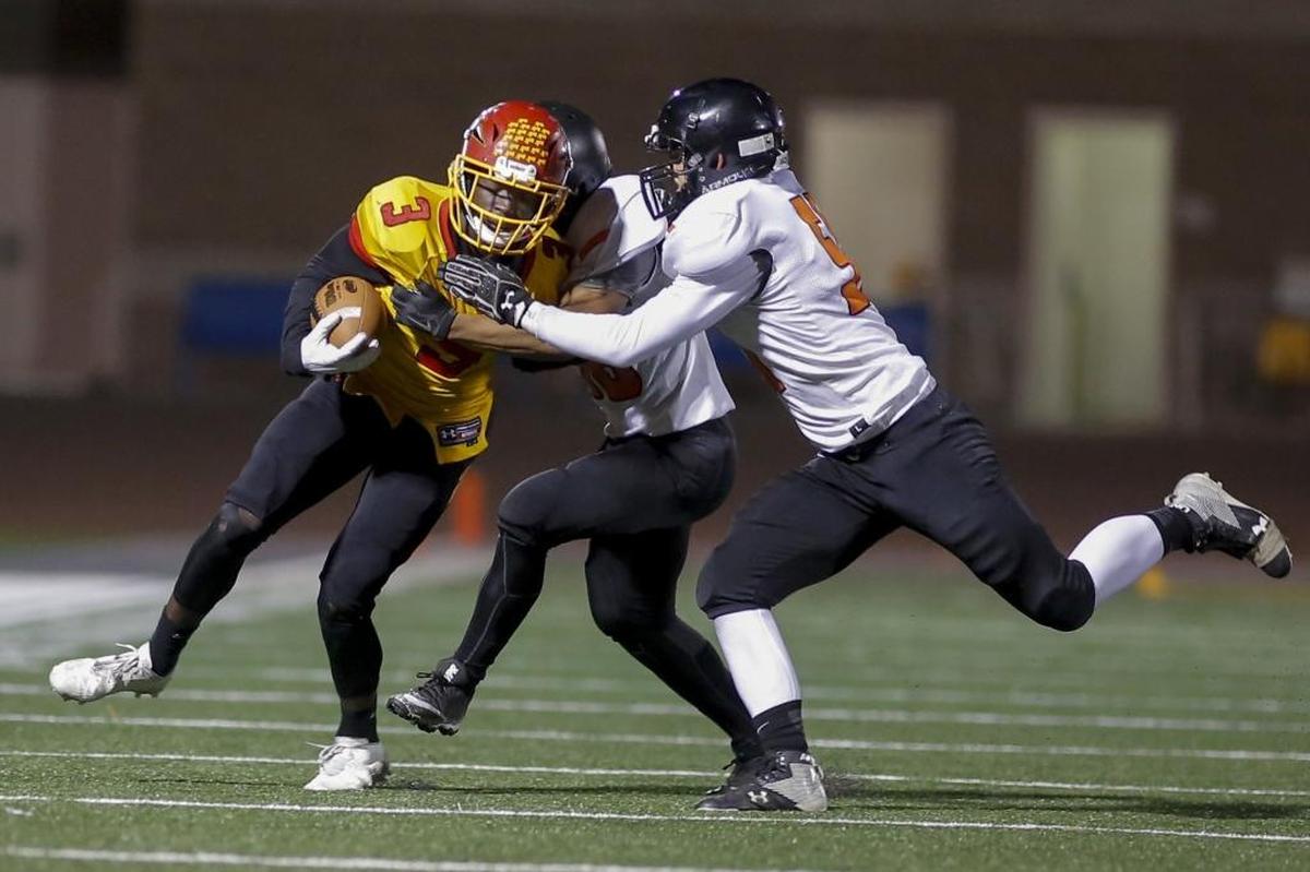 Kamiakin's running back Tuna Altahir (3) runs with the ball while Kennewick's defense Cedric Riel (38) and Tyler Todish (51) close in on him during a Mid-Columbia football game at Lampson Stadium in Kennewick on Friday.