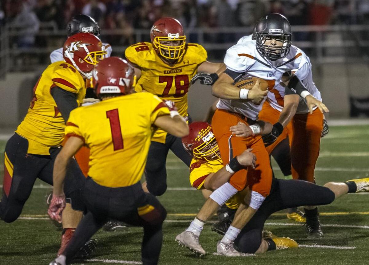 Kamiakin Braves defenders Kelen Rutz (1), Michael Wymore (44), Tyler Clearly (78) and Tanner Sullins (88) have Kennewick Lions quarterback Blaine Chavez surrounded during Friday night’s Mid-Columbia Conference football game at Lampson Stadium.