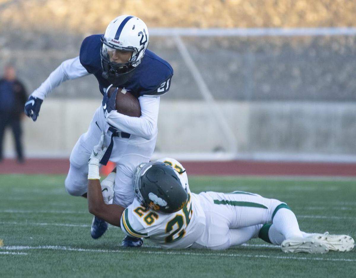 Chiawana receiver Riley Cissne (21) tries to slip through the tackle of Richland’s Stephon Sanders (26).