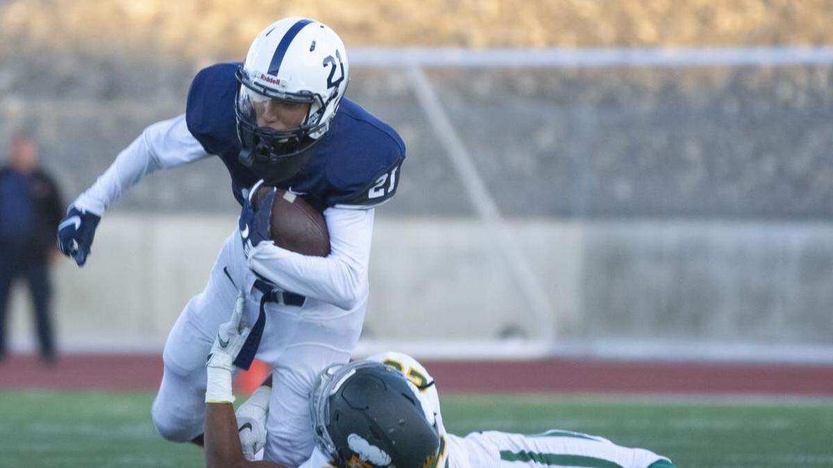 Chiawana receiver Riley Cissne (21) tries to slip through the tackle of Richland’s Stephon Sanders (26).