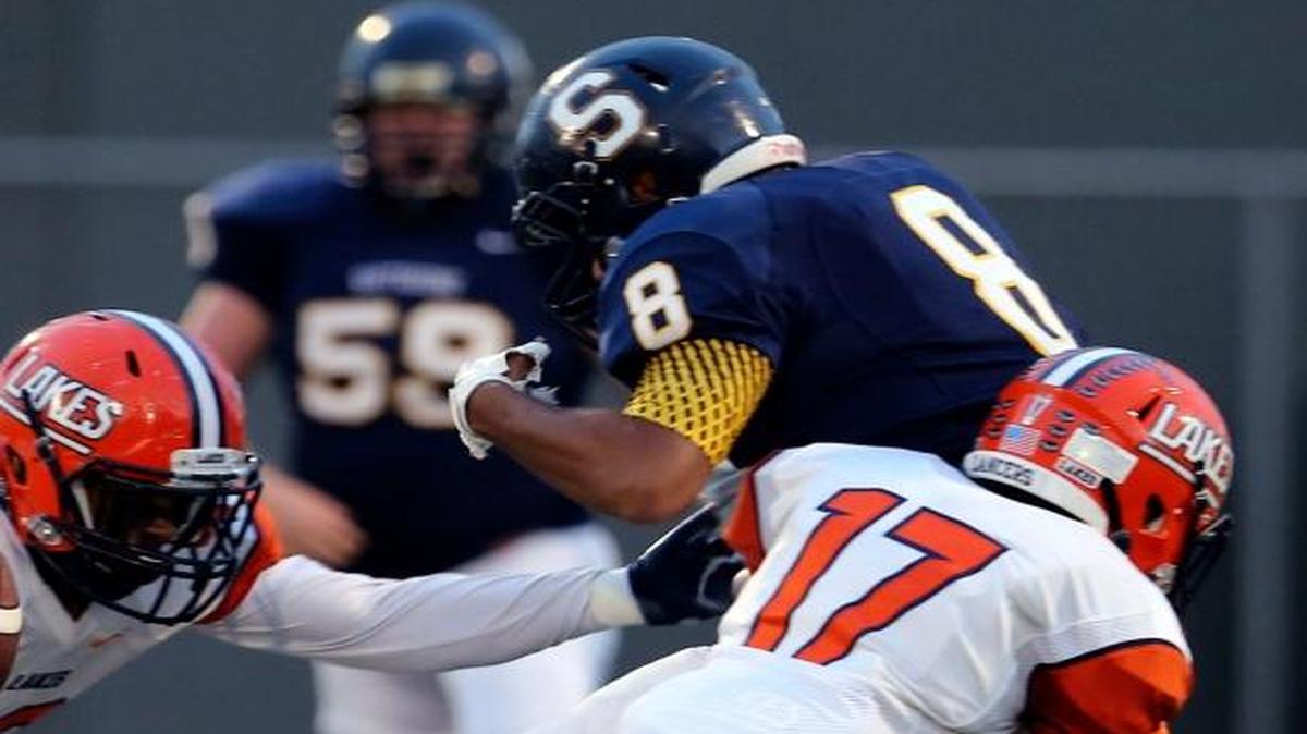 Southridge’s Brycen Kelly (8) has a ball knocked loose by Lakes’ Daytona Comoza (17) and Daeon Hudson (13) during Saturday’s playoff game at Lampson Stadium in Kenenwick.