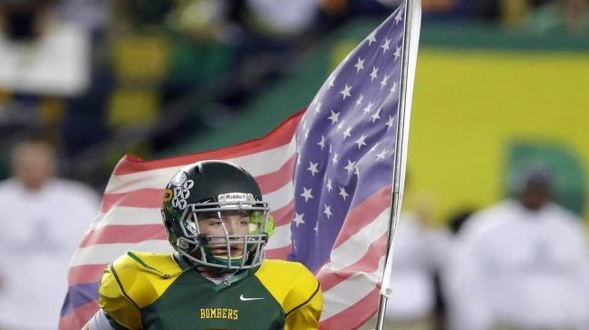 Richland’s Ryan Kriskovich runs with the U.S. flag before the start of the Washington Class 4A high school football championship against Camas, Dec. 3 in Tacoma, Wash. The flag, which featured one blue stripe, was a symbol of solidarity with the Tacoma Police Department after officer Reginald “Jake” Gutierrez was killed by a gunman Nov. 30.