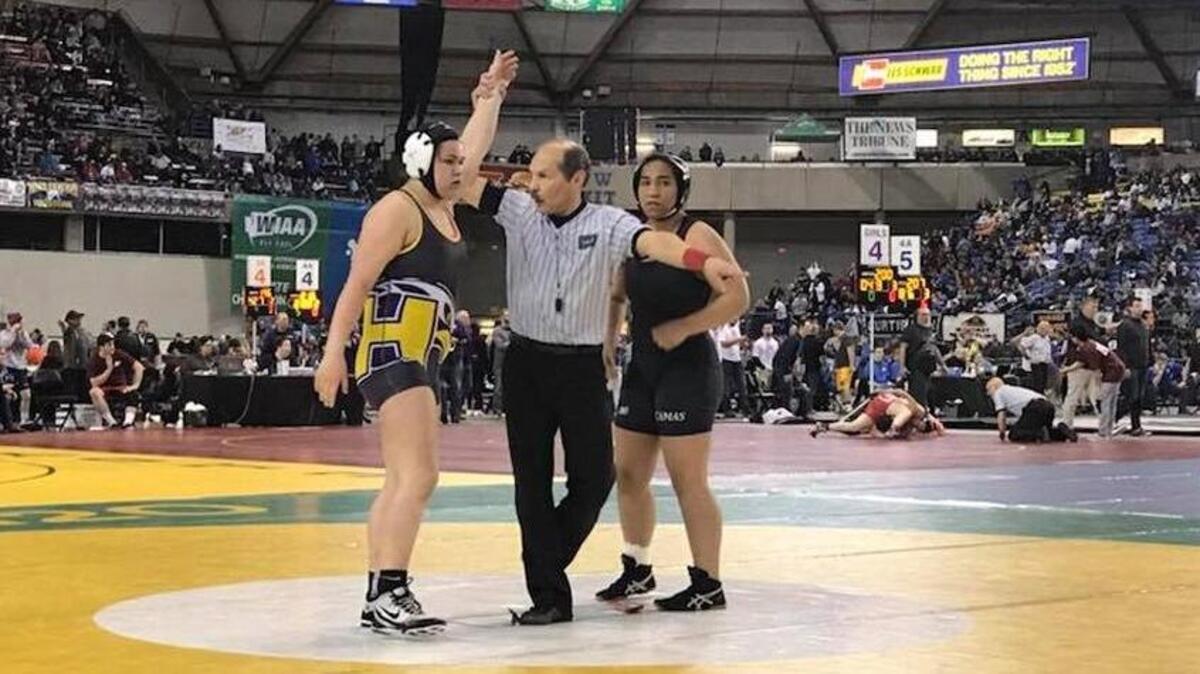Hanford’s Grace Nelson gets her hand raised after pinning Madeline Moore of Camas in a 190-pound consolation match Friday at Mat Classic at the Tacoma Dome.