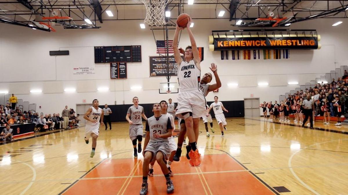 Kennewick High School’s Dillon Plew (22) flies to the basket over Moses Lake’s Isaiah Thomas and Ricardo Gonzalez (23) on Friday night at the Lions Den in Kennewick.