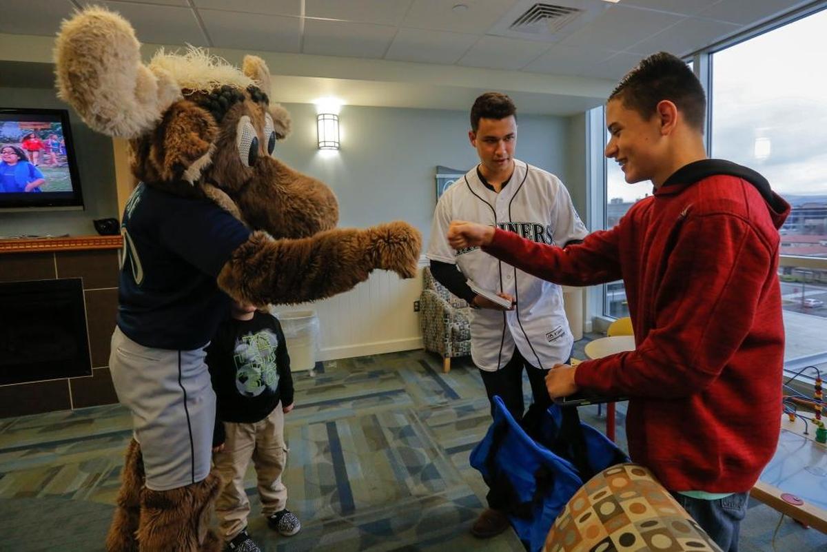Seattle Mariners mascot, Mariner Moose, fist bumps Juan Ramos, 13, as Mariners pitcher, Marco Gonzales, center, hands him an autographed photo Friday at Kadlec Regional Medical Center in Richland.