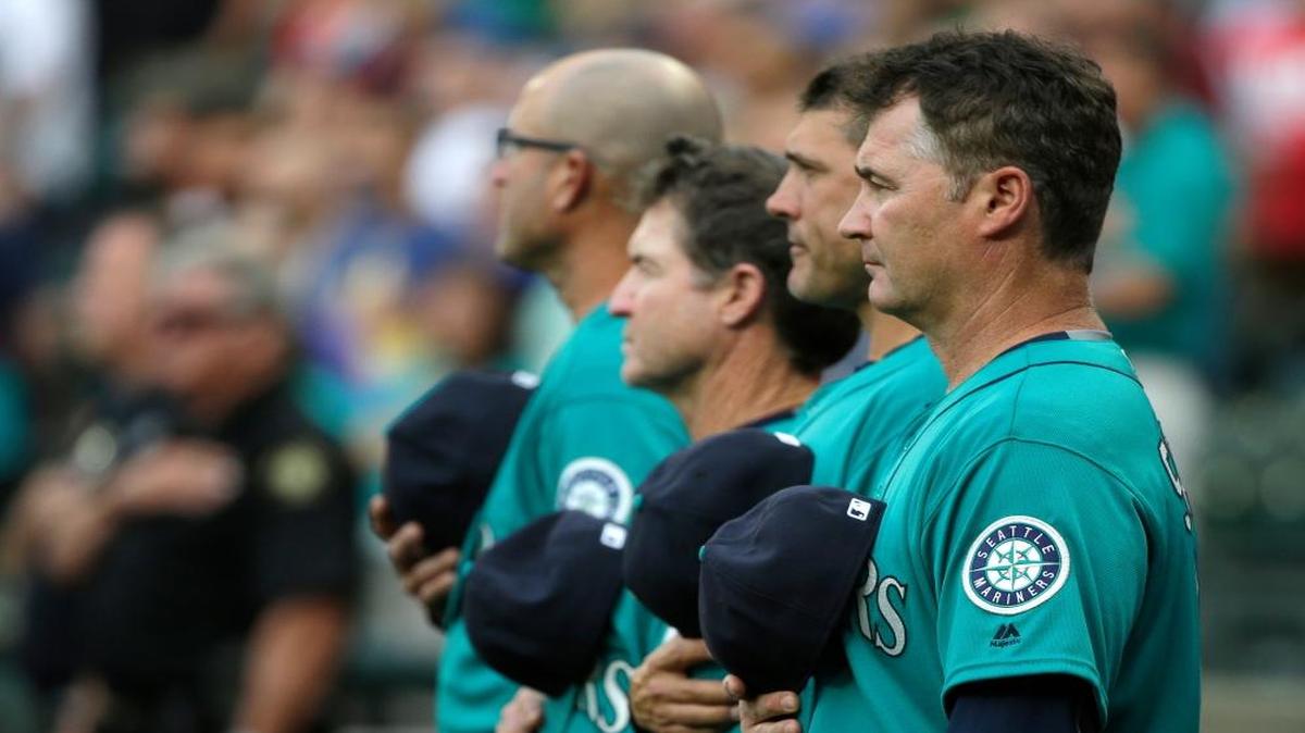 Seattle Mariners manager Scott Servais, right, stands with several Mariners coaches during the singing of the national anthem before a baseball game against the Los Angeles Angels on Friday.
