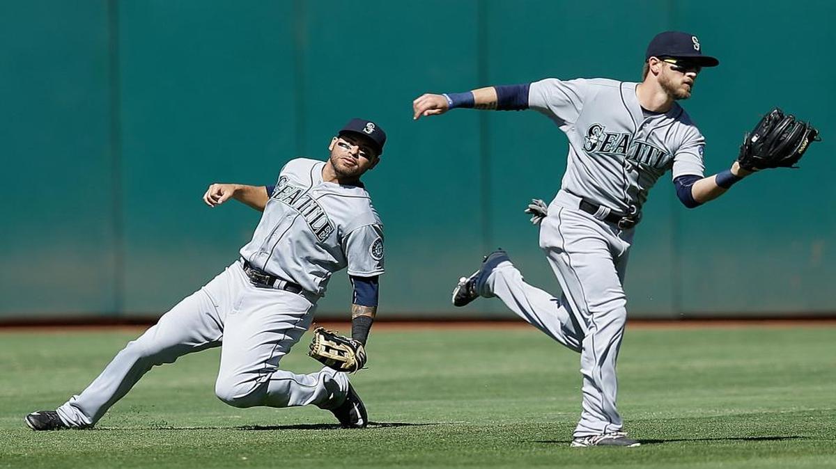 
Seattle center fielder Shawn O'Malley, right, catches a ball in front of right fielder Stefen Romero in the seventh inning of Sunday’s game in Oakland. O’Mally continued his impressive play with the Mariners, going 1-for-2 and scoring a run, one night after the Kennewick native hit his first big-league home run.
