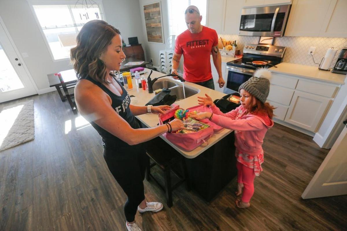 Sarah Howell helps her daughter, Paisley Howell, 7, pack a play bag for their upcoming family trip as her husband, Jerad Howell, cleans up and loads the truck at their Pasco home.